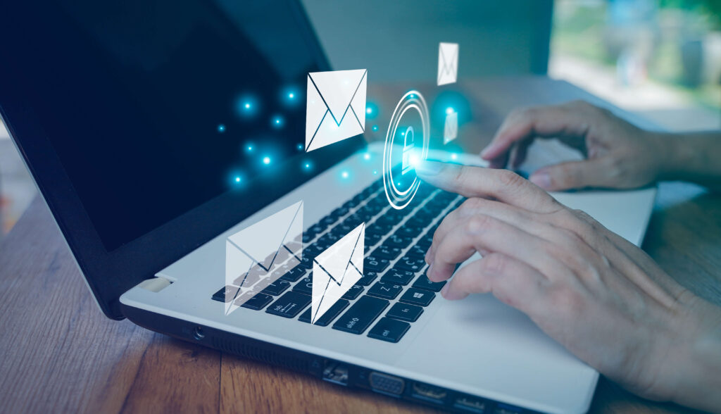 Man types on laptop with email icons superimposed