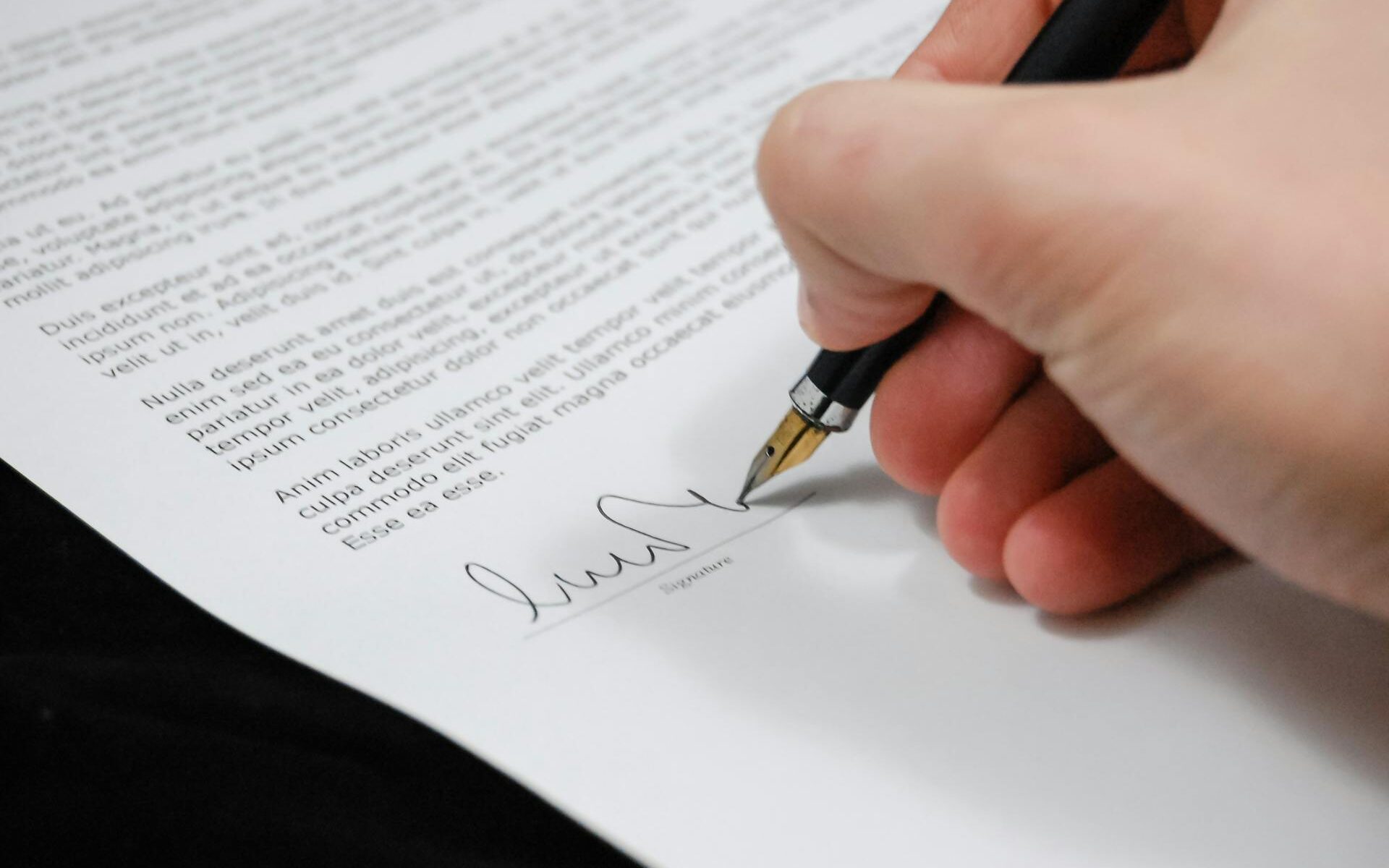 Man with a pen in his hand signs a legal contract