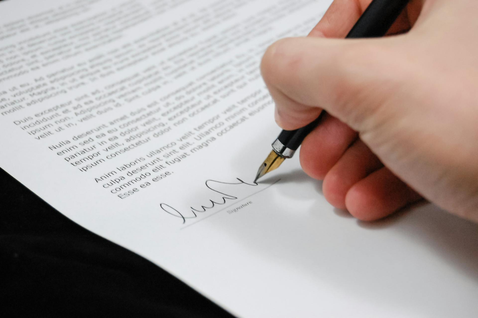 Man with a pen in his hand signs a legal contract